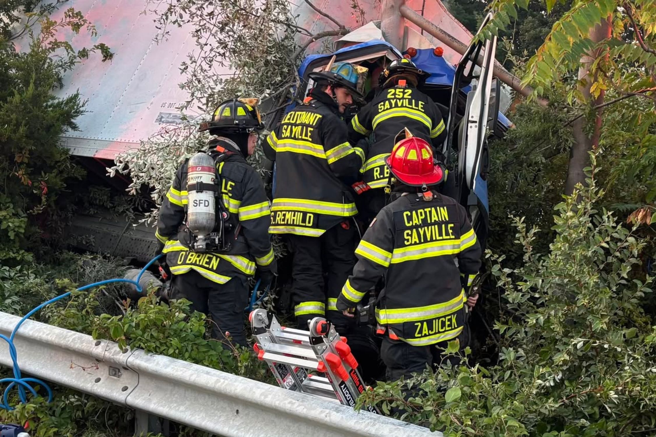 Sayville firefighters work to extricate a driver from a damaged box truck on Sunrise Highway.
