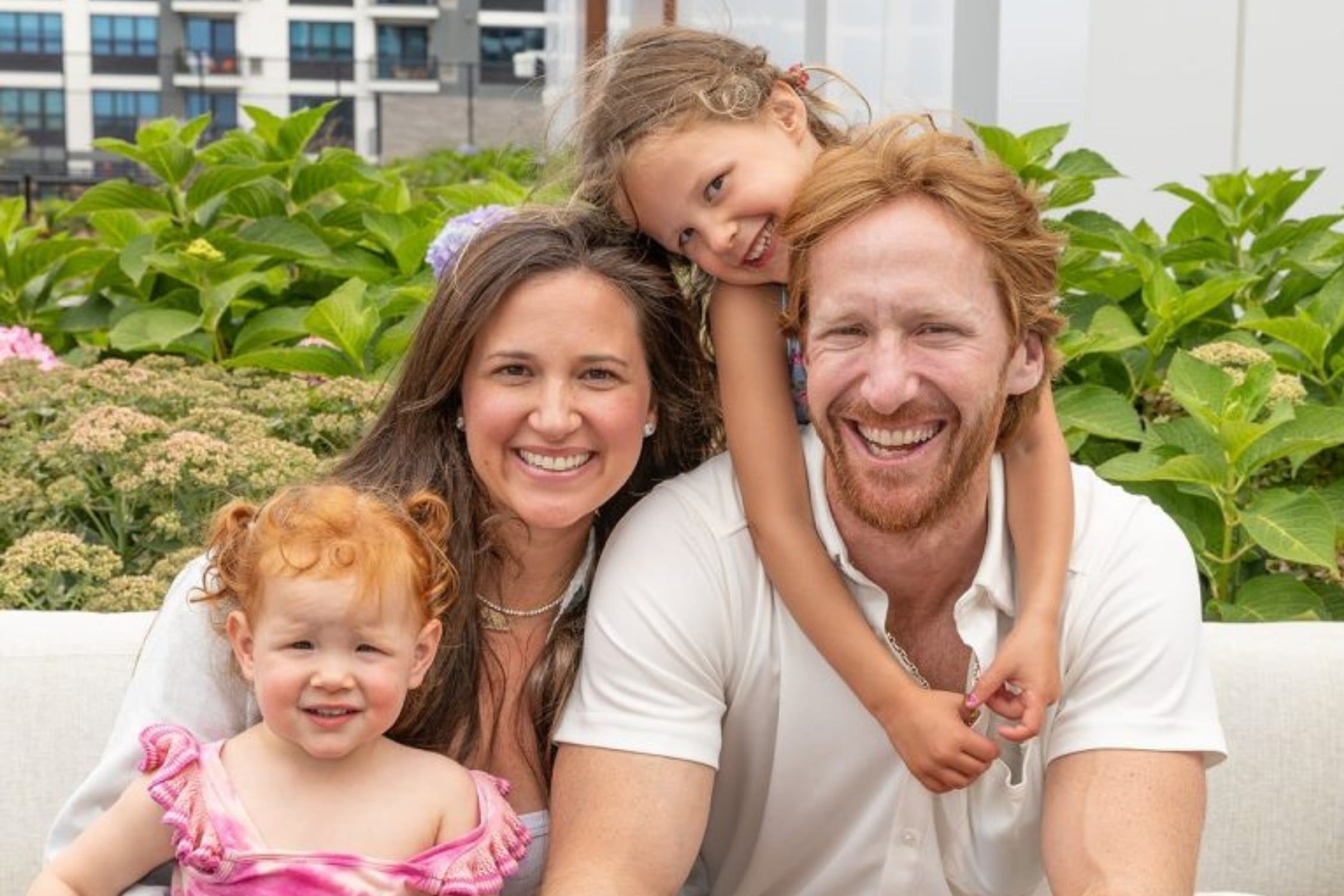 Spencer Korwin smiling with his wife Carly and their two young daughters.