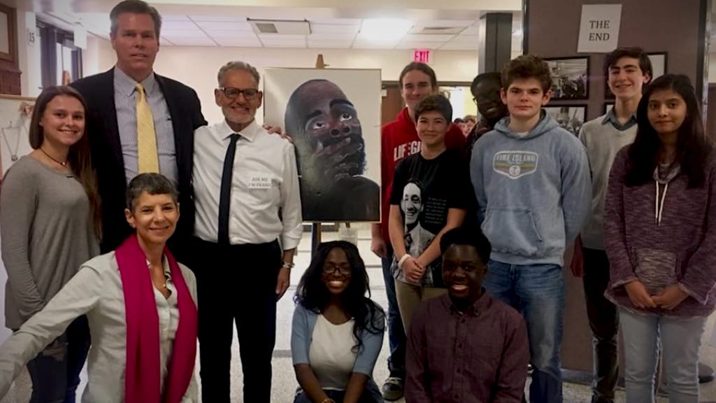 Photo:"Frank Speaking" Frank Romeo (center) with his artwork, titled "Why," Bay Shore School Superintendent Joseph C. Bond, and students from Bay Shore High School. Photo courtesy of Frank Romeo.