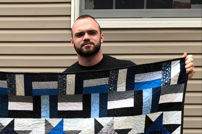 Man standing holding up a blanket.